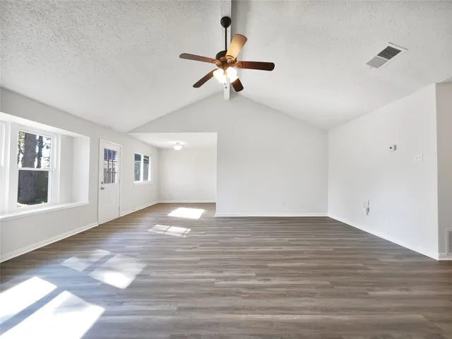 a view of an empty room with a window and wooden floor