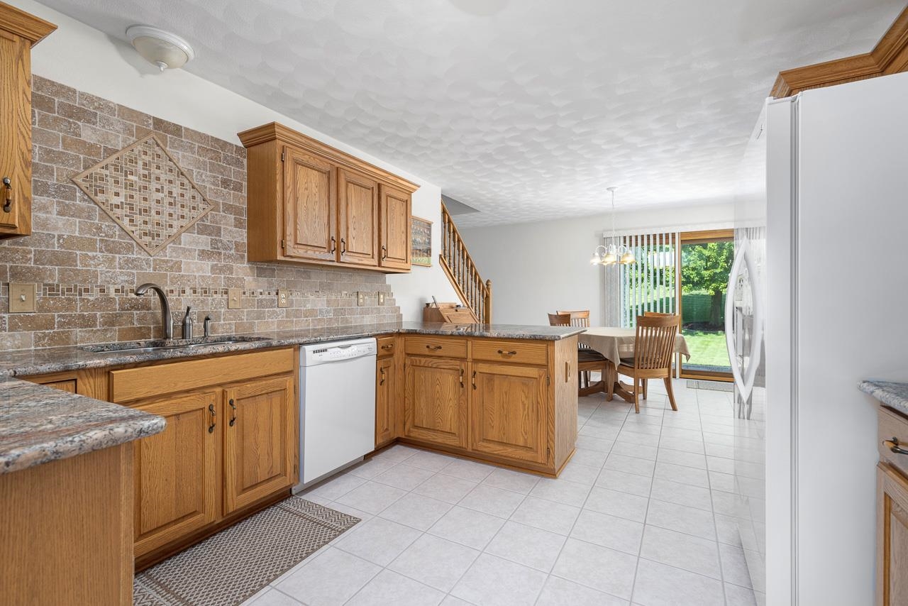 9899 Rambouillet Ridge Roscoe, IL 61073 - Photo 18 of 32 a kitchen with a sink a table and chairs in it