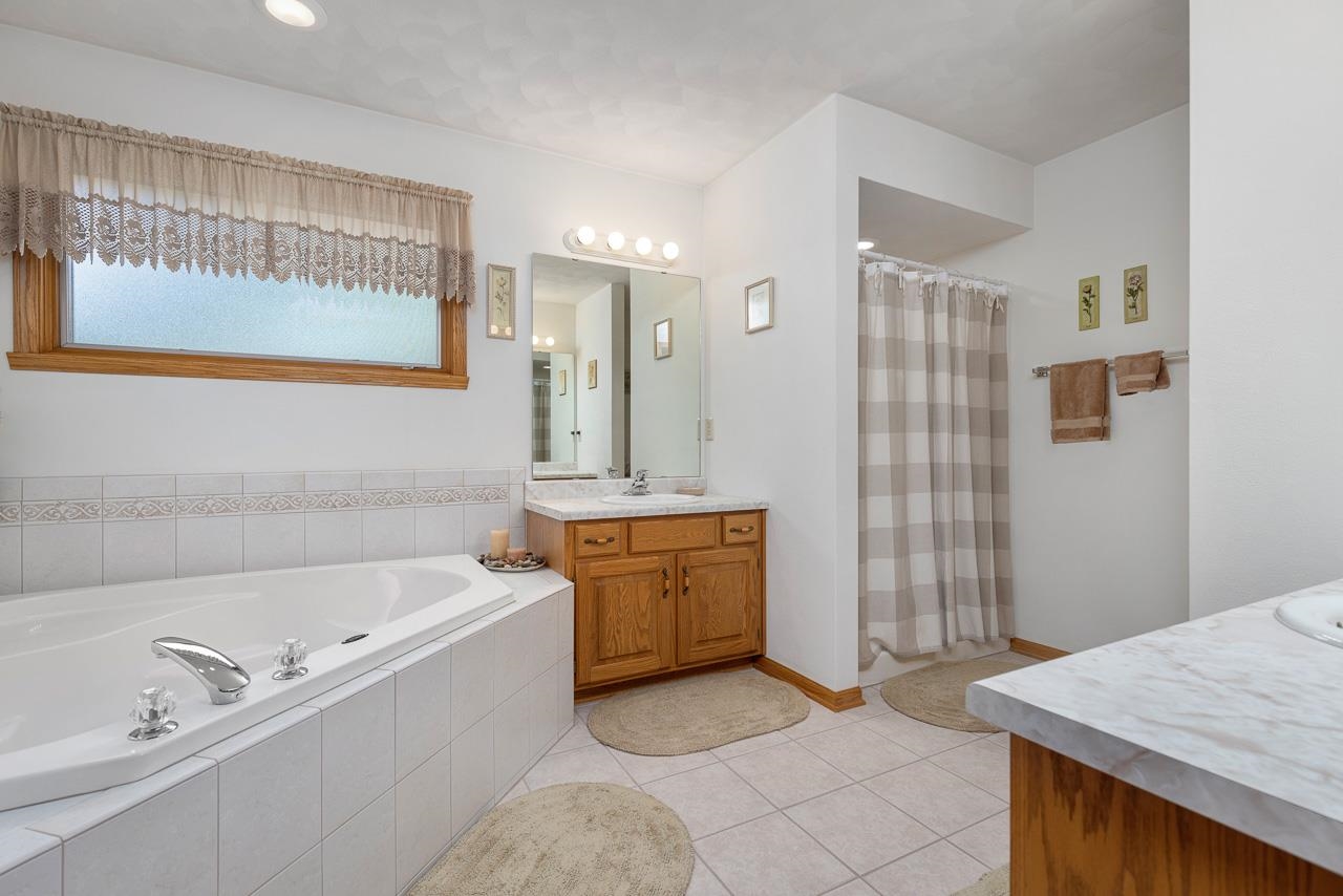 9899 Rambouillet Ridge Roscoe, IL 61073 - Photo 24 of 32 a bathroom with a tub a sink and mirror