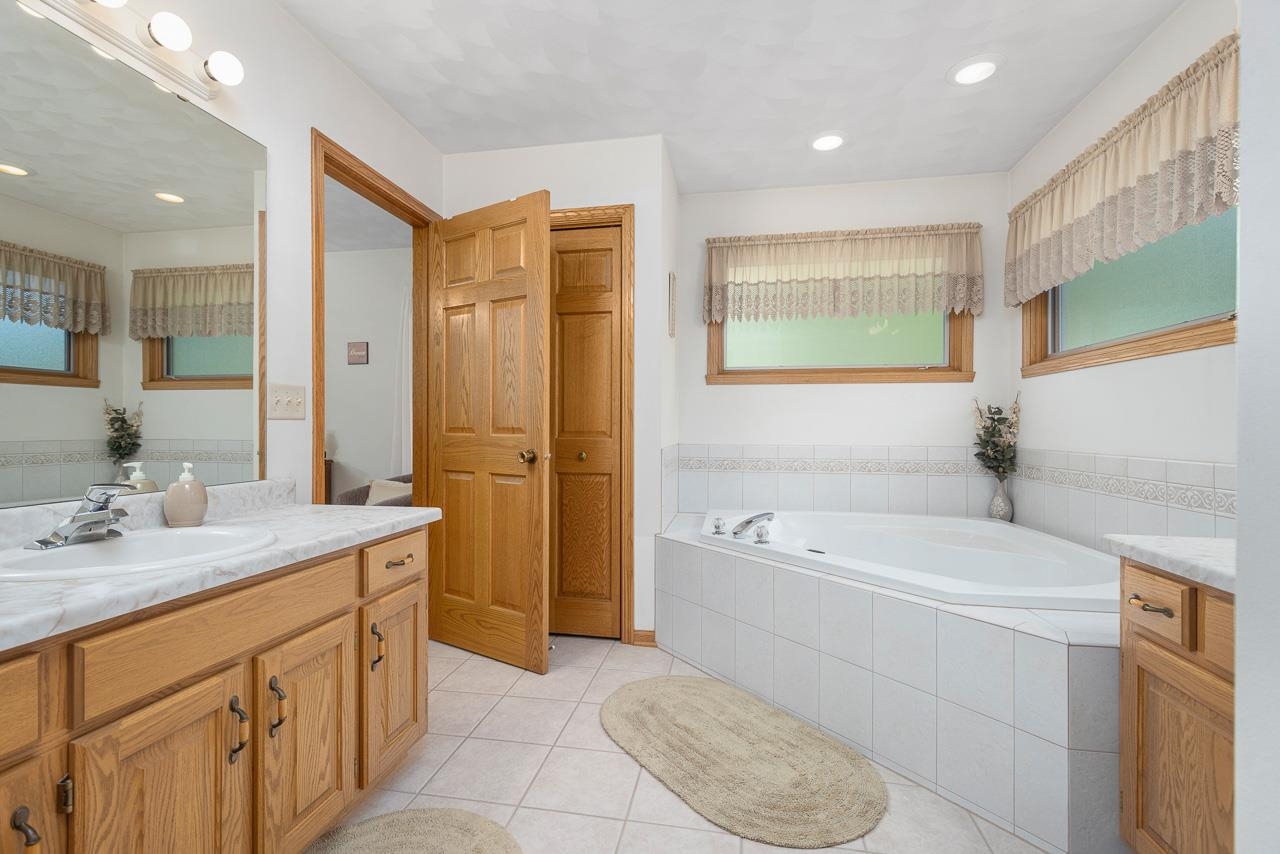 9899 Rambouillet Ridge Roscoe, IL 61073 - Photo 25 of 32 a spacious bathroom with a tub sink shower and mirror