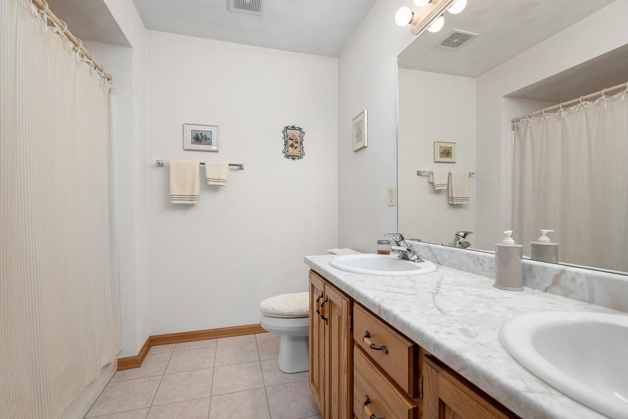 9899 Rambouillet Ridge Roscoe, IL 61073 - Photo 28 of 32 a bathroom with a granite countertop sink a toilet and a mirror