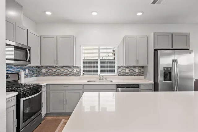 a kitchen with stainless steel appliances granite countertop a stove a sink and a refrigerator