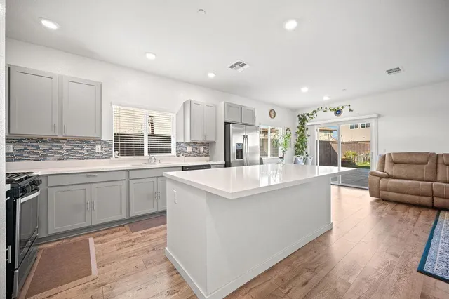 a large white kitchen with a stove a sink a dining table and chairs