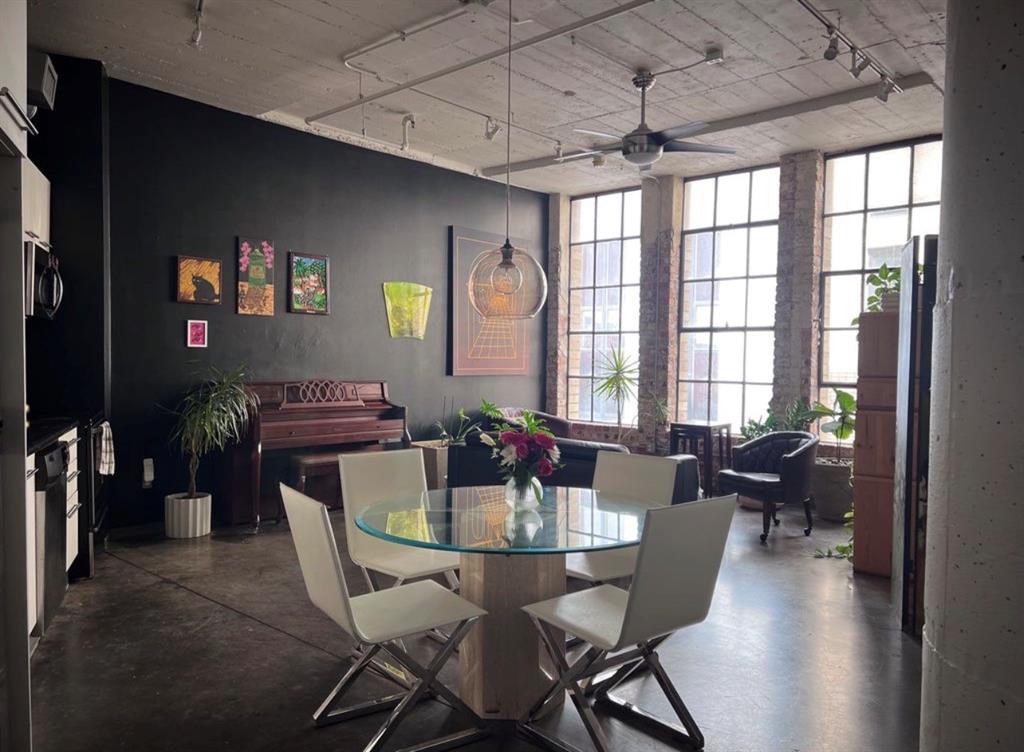 1122 Jackson Street, Unit 514 Dallas, TX 75202 - Photo 9 of 40 Industrial-style interior featuring high ceilings with exposed concrete, large grid-pattern windows, and polished concrete flooring