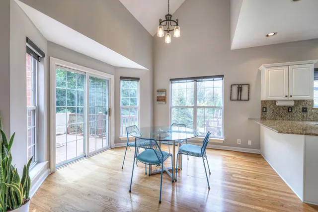 a kitchen with stainless steel appliances granite countertop a stove top oven a sink dishwasher and white cabinets with wooden floor