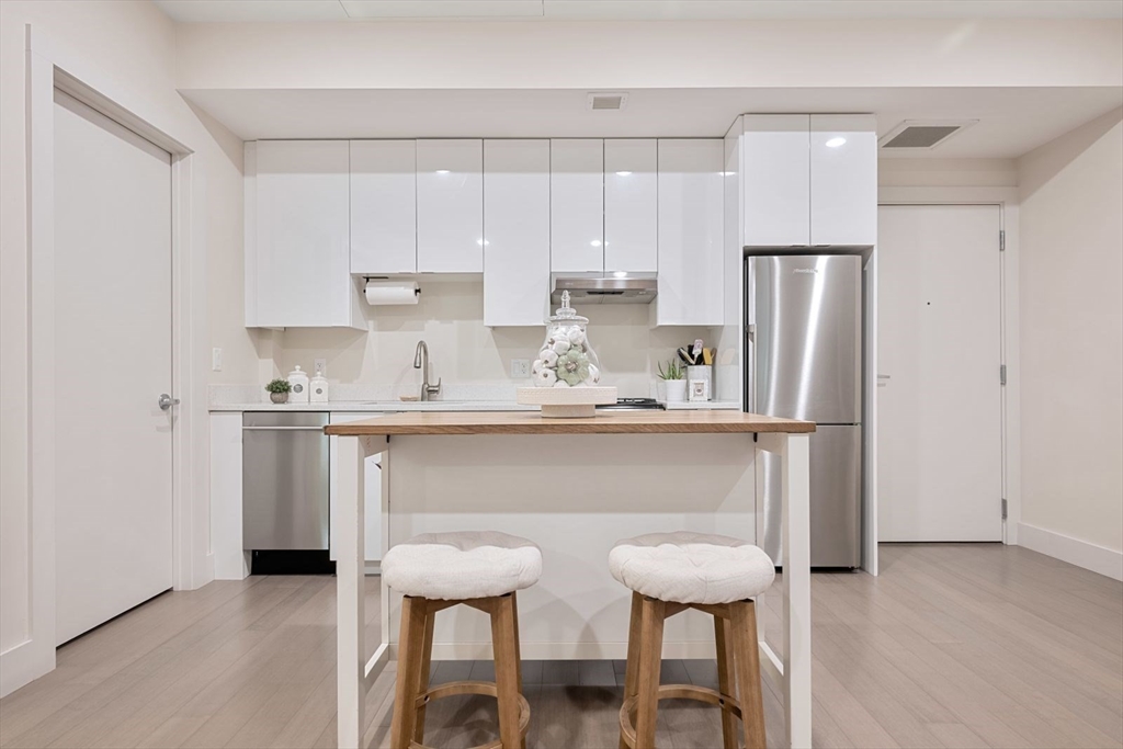 121 Portland Street, Unit 605 Boston, MA 02114 - Photo 4 of 19 a kitchen with stainless steel appliances a refrigerator a sink and white cabinets