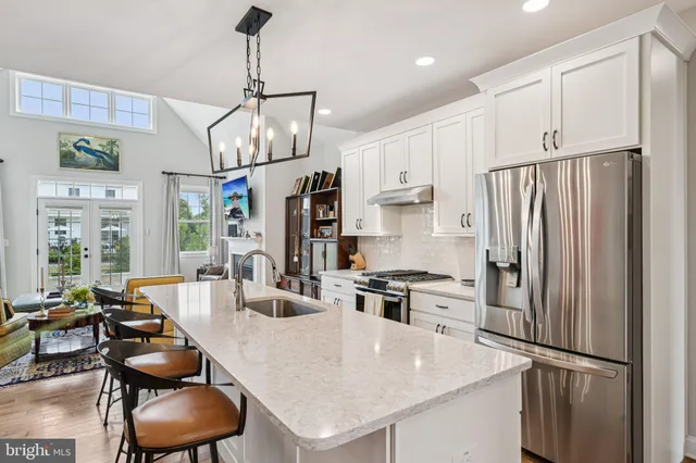 a kitchen with stainless steel appliances a refrigerator a stove a sink a dining table and chairs