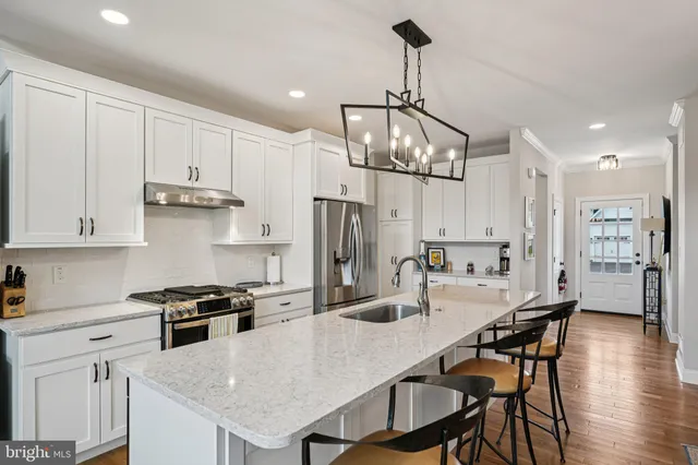 a kitchen with stainless steel appliances granite countertop a stove a refrigerator a kitchen island a sink and chairs