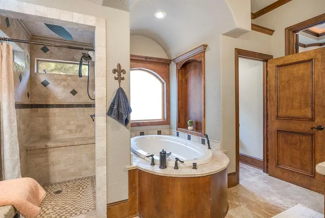 a bathroom with a tub a mirror and a shower