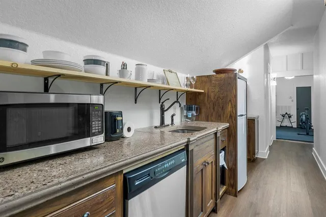 a kitchen with stainless steel appliances granite countertop a lot of cabinets and wooden floor