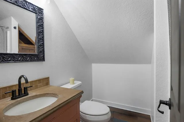 a bathroom with a granite countertop toilet sink and mirror