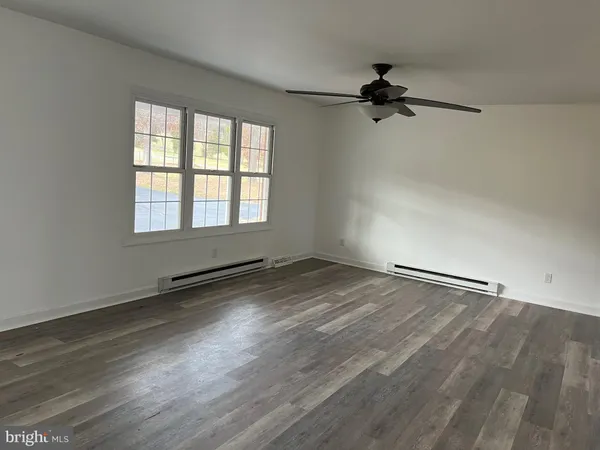 an empty room with wooden floor and windows