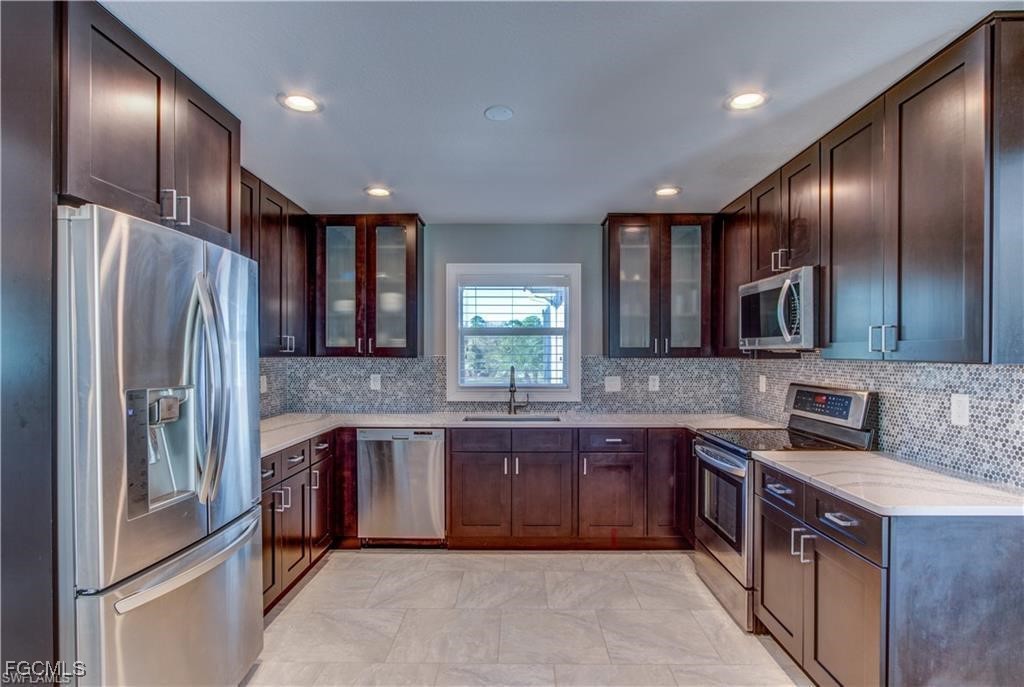 20051-071 Welborn Road North Fort Myers, FL 33917 - Photo 24 of 35 a large kitchen with stainless steel appliances granite countertop a refrigerator a sink a stove a washer dryer and wooden cabinets