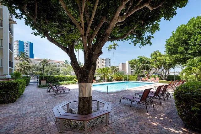 a view of a backyard with table and chairs potted plants and a large tree