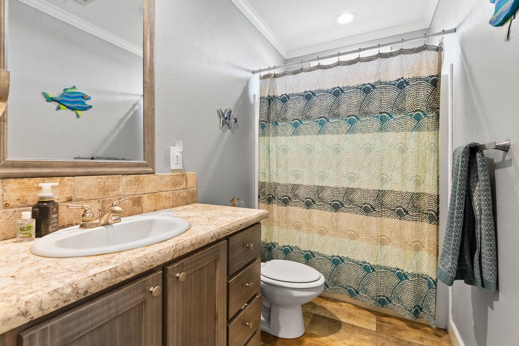 159 Copano Ridge Road Rockport, TX 78382 - Photo 23 of 31 a bathroom with a granite countertop sink a toilet a mirror and shower