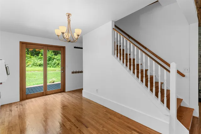 a view of an empty room with wooden floor and fan