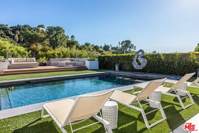 a view of swimming pool with seating area and trees in the background