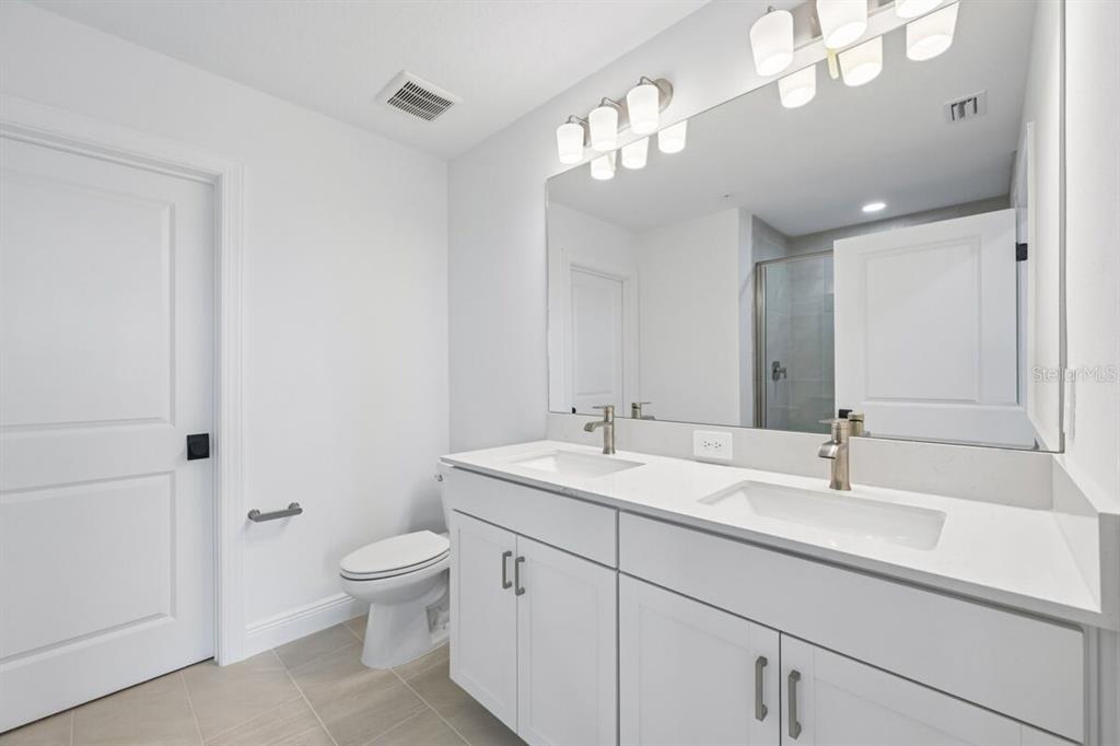 17712 Broadleaf Loop Venice, FL 34293 - Photo 9 of 23 a bathroom with a toilet a sink and mirror