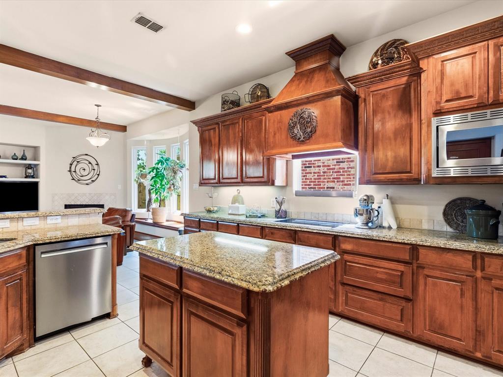 1615 Roma Lane Allen, TX 75013 - Photo 7 of 36 Spacious kitchen featuring rich wood cabinetry, granite countertops, stainless steel appliances, and a central island