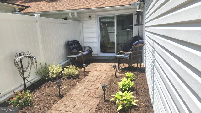 a view of a white house with a large tree and wooden fence