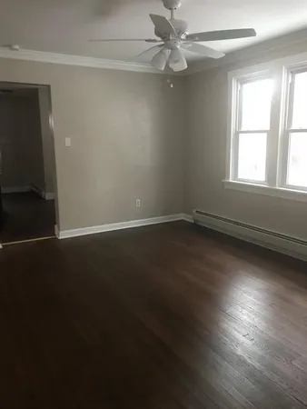 an empty room with wooden floor fan and windows