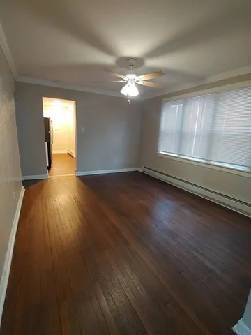a view of empty room with wooden floor and fan