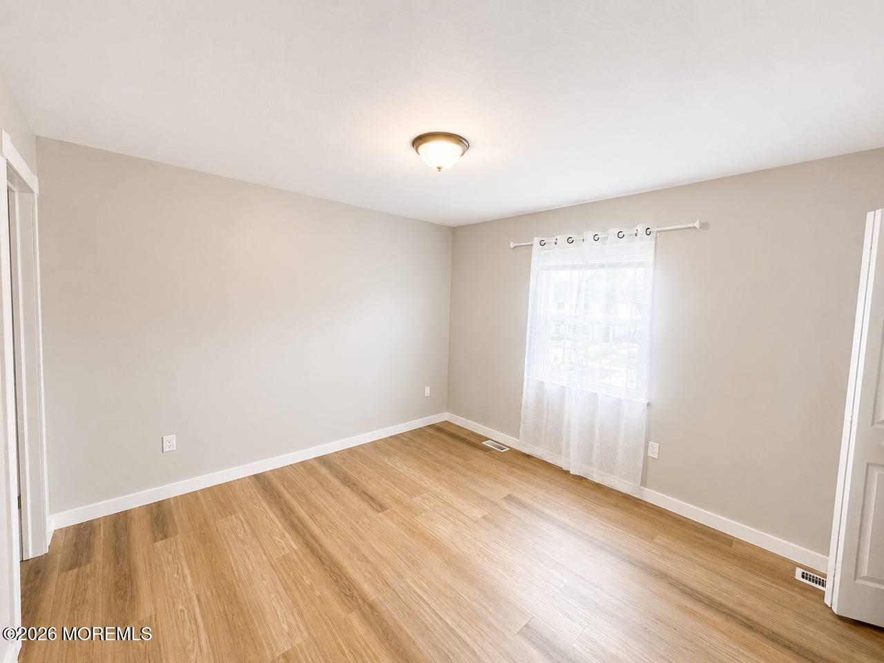 1144 Sawmill Road, Unit 121 Brick, NJ 08724 - Photo 18 of 23 an empty room with wooden floor and windows