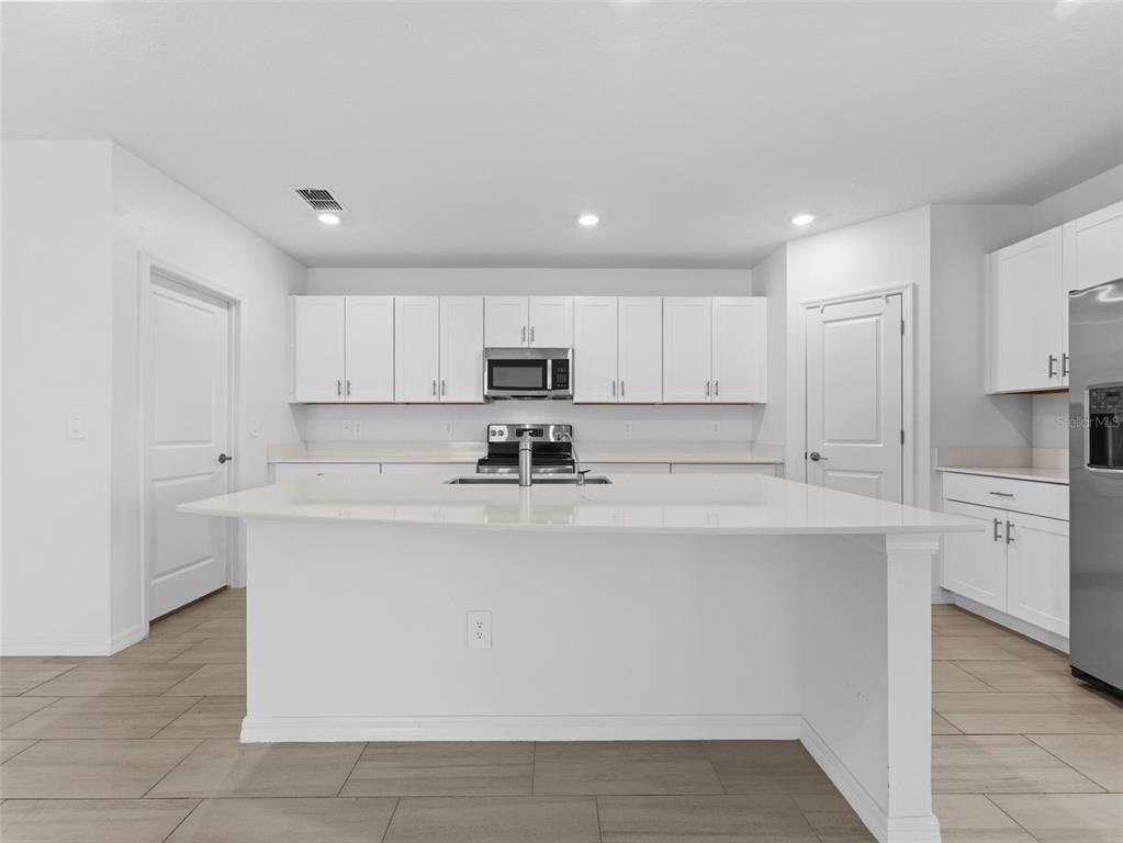 11628 Radiant Shr Loop San Antonio, FL 33576 - Photo 4 of 16 a view of kitchen with stainless steel appliances granite countertop a stove top oven a sink and white cabinets
