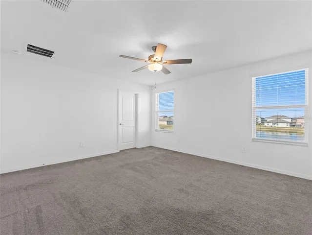 a view of an empty room with a ceiling fan and window