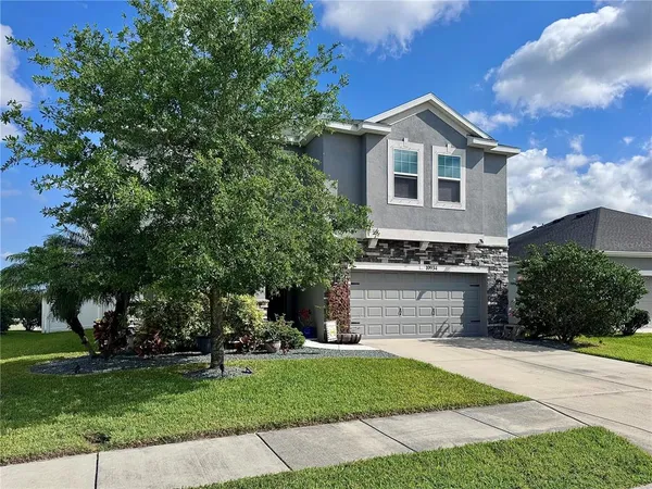 a front view of a house with a garden and trees