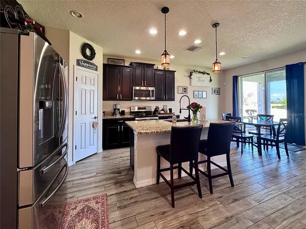 a kitchen with stainless steel appliances granite countertop a refrigerator a stove a sink a dining table and chairs