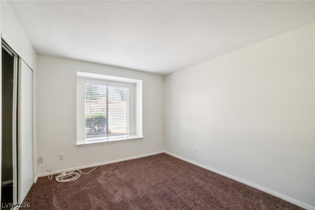 7200 West Pirates Cove Road, Unit 1049 Las Vegas, NV 89145 - Photo 4 of 12 Unfurnished bedroom featuring a closet and dark colored carpet