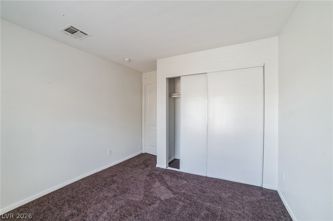 7200 West Pirates Cove Road, Unit 1049 Las Vegas, NV 89145 - Photo 5 of 12 Unfurnished bedroom with dark colored carpet and a closet