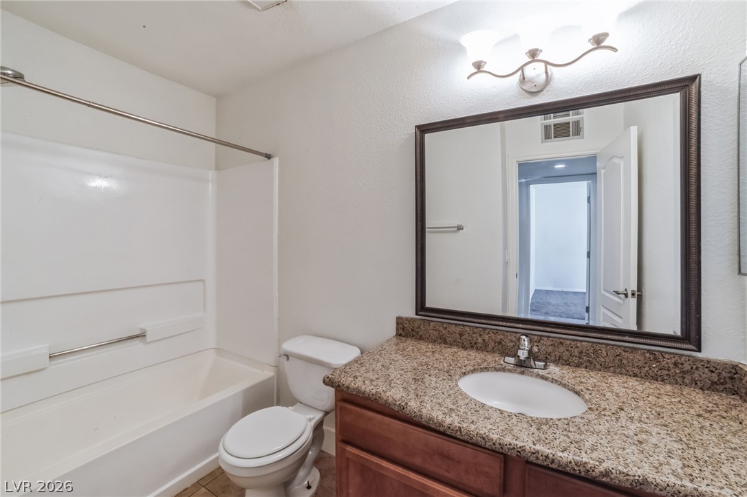 7200 West Pirates Cove Road, Unit 1049 Las Vegas, NV 89145 - Photo 6 of 12 Bathroom featuring vanity, washtub / shower combination, and a textured wall