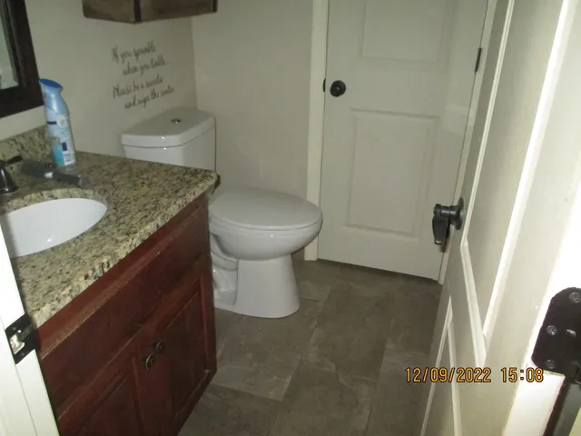 a bathroom with a granite countertop sink a toilet and shower