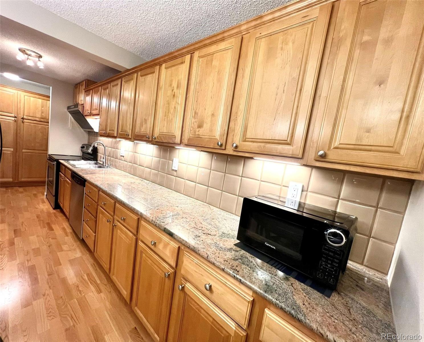 2 Adams Street, Unit 604 Denver, CO 80206 - Photo 12 of 41 a kitchen with stainless steel appliances wooden cabinets and a stove top oven