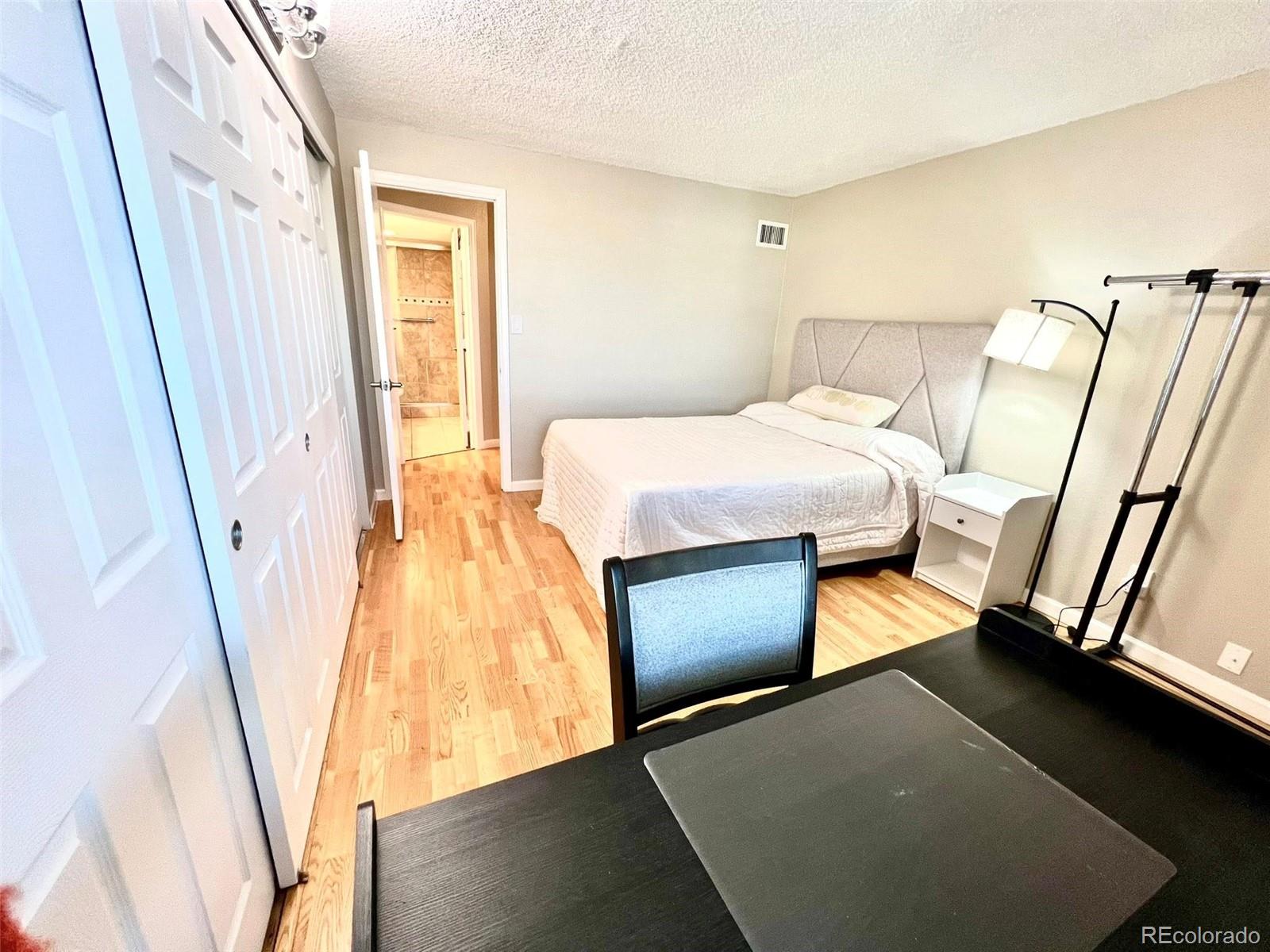 2 Adams Street, Unit 604 Denver, CO 80206 - Photo 18 of 41 a bedroom with a bed and a flat tv screen on a dresser