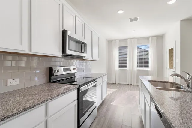 a kitchen with stainless steel appliances granite countertop a sink stove microwave and cabinets