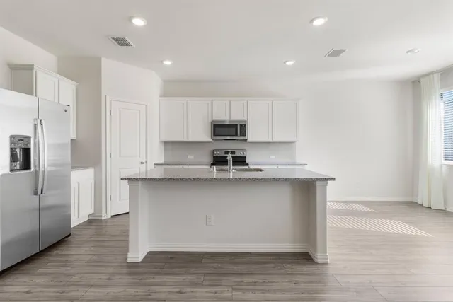 a kitchen with stainless steel appliances granite countertop a sink a stove a refrigerator and cabinets