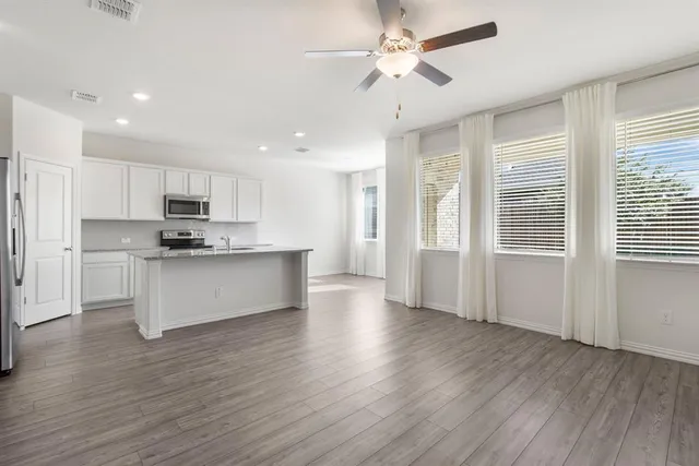 a view of kitchen with granite countertop appliances cabinets and a wooden floor