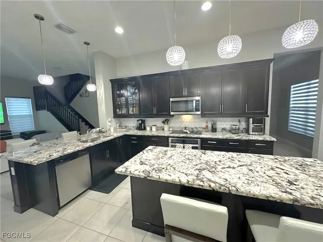 a kitchen with granite countertop a sink a counter top space appliances and cabinets