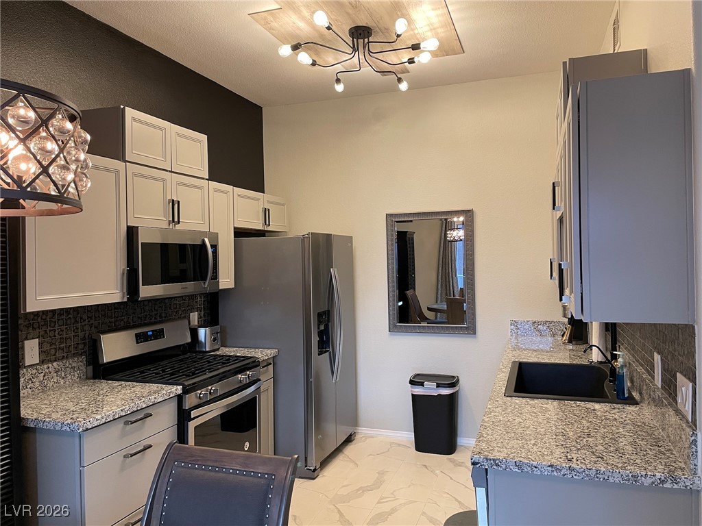 700 Carnegie Street, Unit 4112 Henderson, NV 89052 - Photo 3 of 21 Kitchen featuring a chandelier, decorative backsplash, stainless steel appliances, light stone counters, and light marble finish flooring