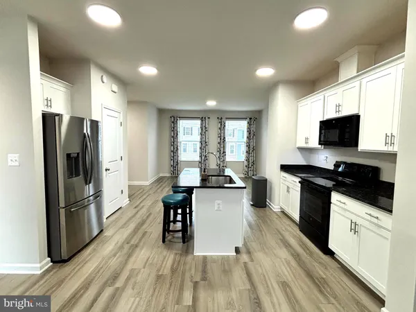 a kitchen with granite countertop a refrigerator stove and sink