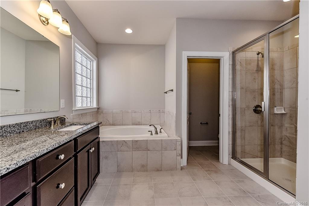5157 Waterloo Drive, Unit CC151 Tega Cay, SC 29708 - Photo 17 of 21 a spacious bathroom with a granite countertop tub sink shower and mirror