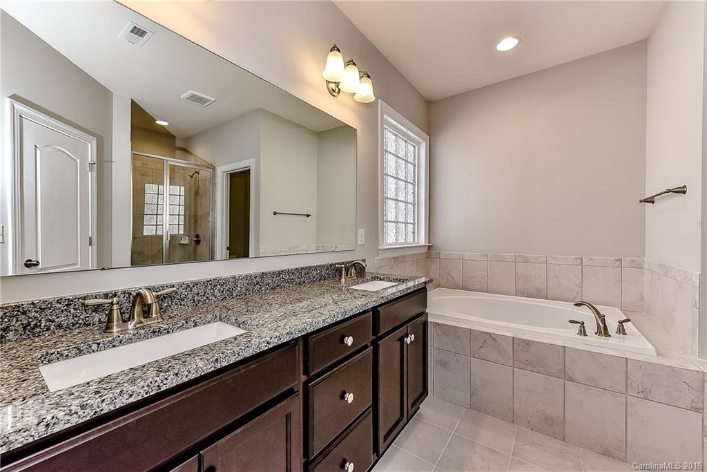 5157 Waterloo Drive, Unit CC151 Tega Cay, SC 29708 - Photo 19 of 21 a bathroom with a granite countertop bathtub a double vanity sink and mirror