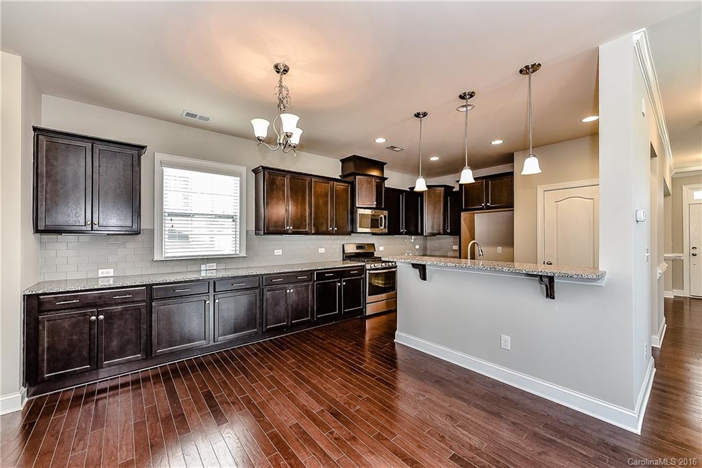 5157 Waterloo Drive, Unit CC151 Tega Cay, SC 29708 - Photo 6 of 21 a kitchen with stainless steel appliances kitchen island granite countertop a stove a sink and a microwave