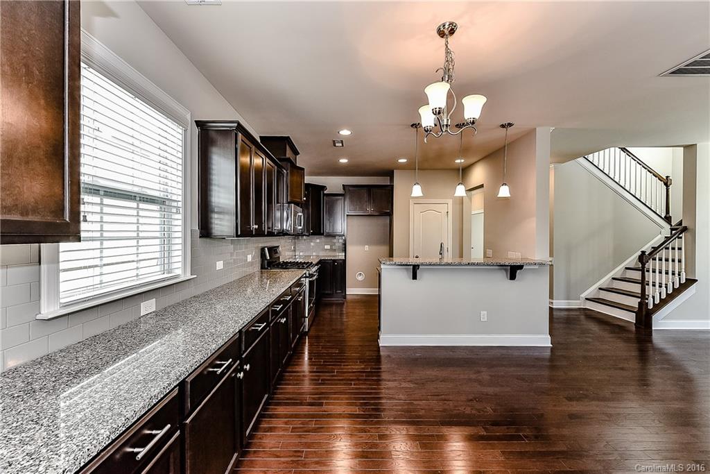 5157 Waterloo Drive, Unit CC151 Tega Cay, SC 29708 - Photo 7 of 21 a large kitchen with stainless steel appliances granite countertop a stove top oven a sink dishwasher with wooden floor and cabinets