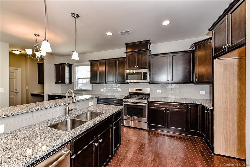 5157 Waterloo Drive, Unit CC151 Tega Cay, SC 29708 - Photo 9 of 21 a kitchen with stainless steel appliances granite countertop a sink a stove and a wooden floors