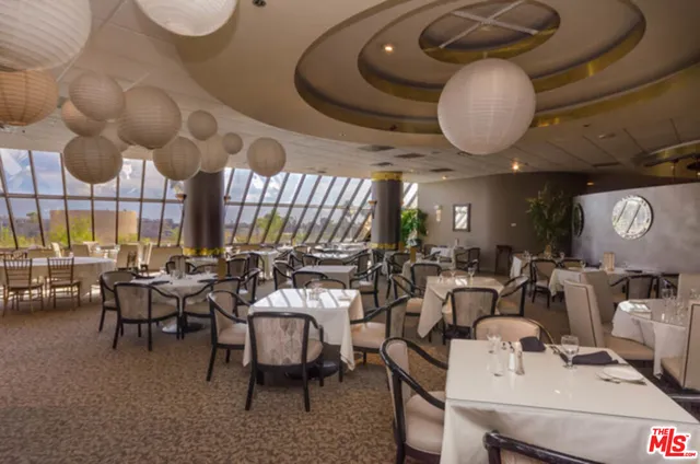 a room with lots of tables a large window and chairs