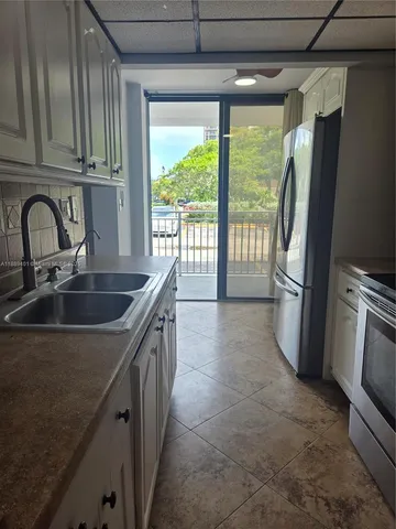 a kitchen with kitchen island granite countertop a sink appliances cabinets and a counter top space